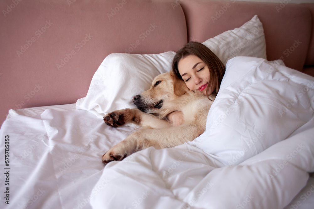 girl in pajamas sleeps in bed with golden retriever dog, woman lies under blanket with pet and dreams girl in pajamas sleeps in bed with golden retriever dog, woman lies under blanket with pet and dreams