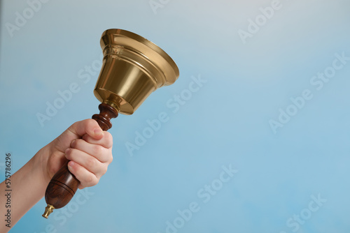 Pupil with school bell on light blue background, closeup. Space for text photo
