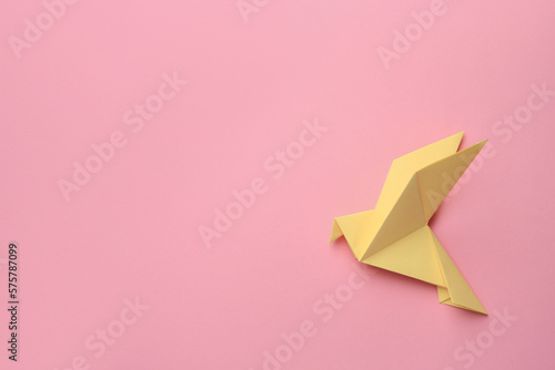 Beautiful yellow origami bird on pink background, top view. Space for text