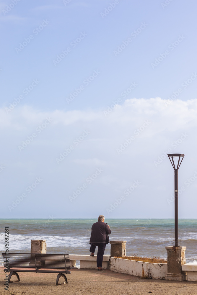 man sitting in front of a rough sea in winter 