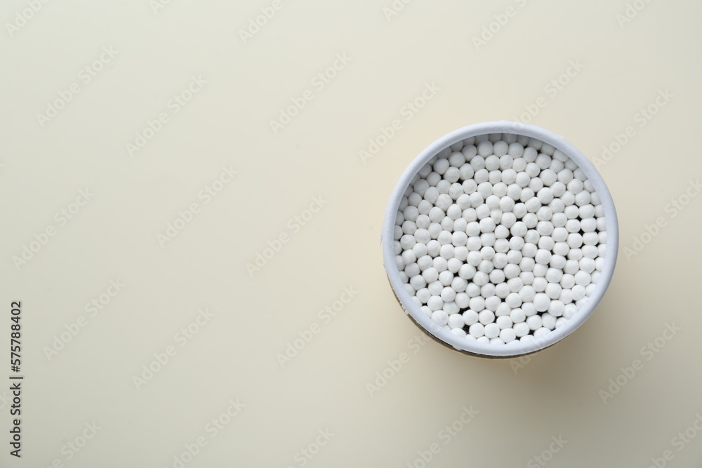 Container with new cotton buds on beige background, top view. Space for text Container with new cotton buds on beige background, top view. Space for text
