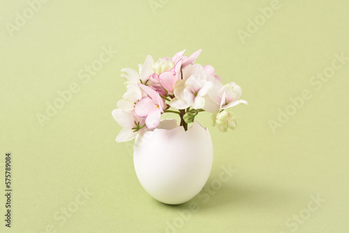 Spring Flowers bouquet in eggshell. Easter greeting card. Light green background  copy space. Spring time concept.