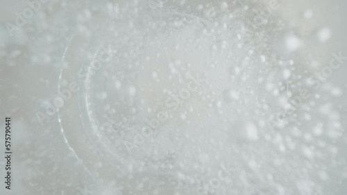 Top down view close-up effervescent tablet in glass of water slow motion shot, white round bubbling aspirin in water, pill dissolves with bubbles photo
