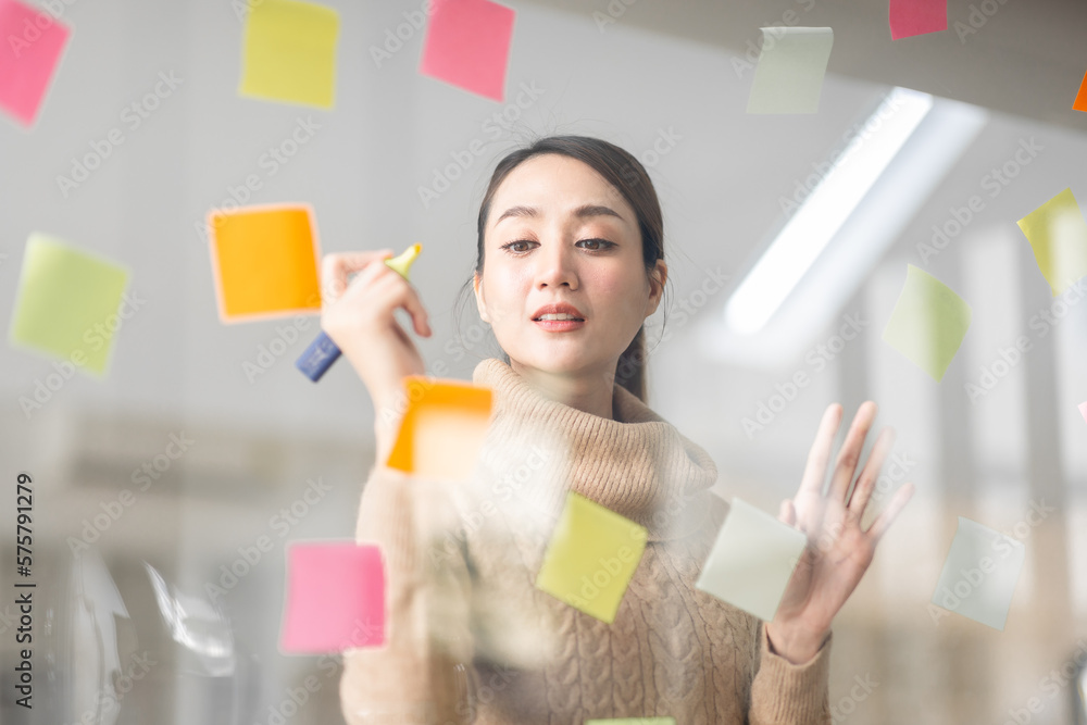 Business Asian woman meeting at office and use post it notes in glass wall to share idea. Brainstorming business office concept. Sticky note on glass wall. Business Asian woman meeting at office and use post it notes in glass wall to share idea. Brainstorming business office concept. Sticky note on glass wall.