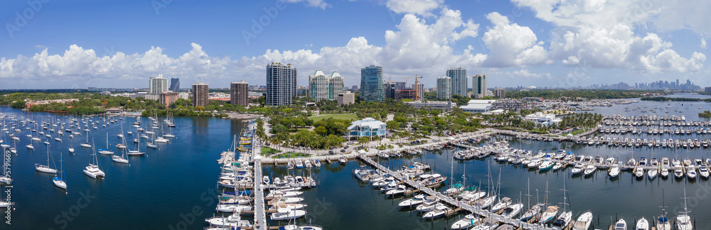 Miami Florida coastal landscape with condominiums and boats against blue sky. Aerial view of city skyline with buildings overlooking yachts at the manmade inland water channel.