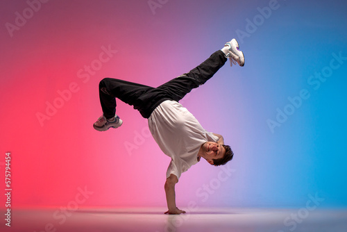 dancer doing acrobatic trick and dancing breakdance in neon red and blue lighting, young energetic guy photo