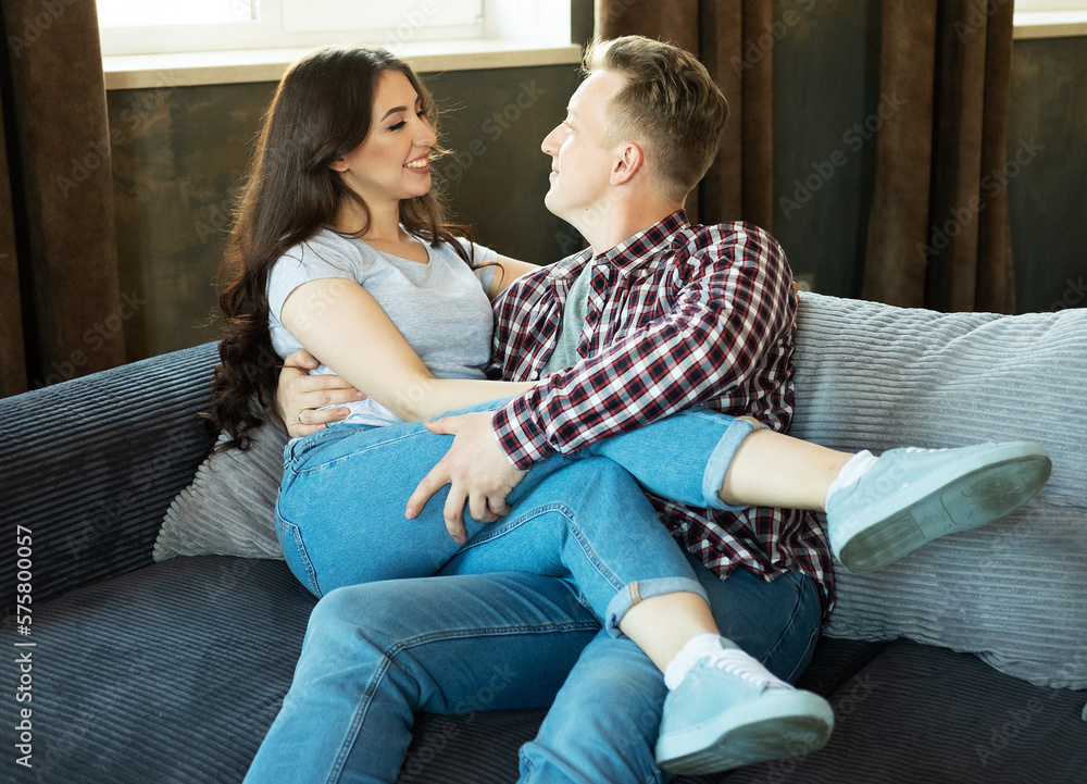 Young beautiful couple is sitting on the couch and hugging. Happy family life. Young beautiful couple is sitting on the couch and hugging. Happy family life.