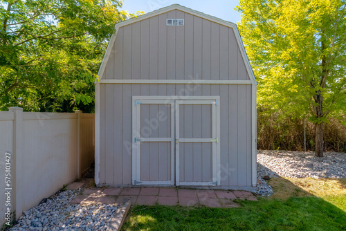 Canvas Print Wooden shed with beige exterior at the yard near the cream-colored fence