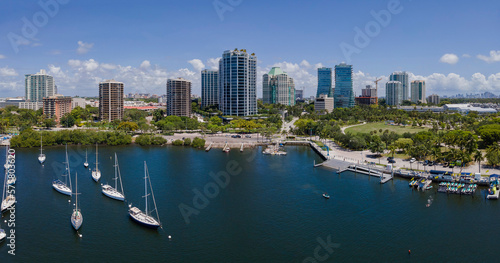 Dinner Key Marina and Coconut Grove Sailing Club on a sunny day in Miami Florida. Aerial view of boats anchored at sea with beautiful city skyline and blue sky in the background. photo
