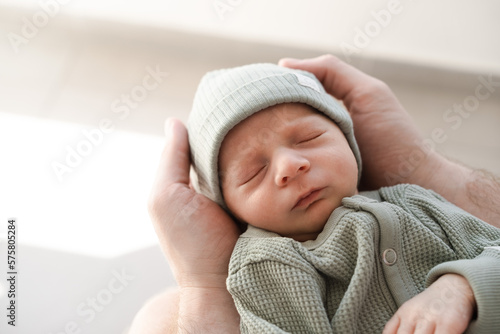 Close up of caucasian hairy brunet cute newborn baby sleeping.One or two week child in male hands.Unrecognizable man, father,holding child.Care,love,happiness concept.