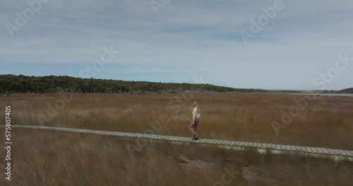 Female traveler visiting Tautuku Estuary walkway in New Zealand, aerial photo