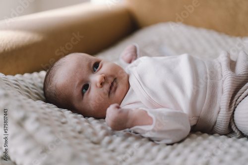 Portrait of a 1 month old baby. Cute newborn baby lying on a developing rug. Love baby. Newborn baby and mother.