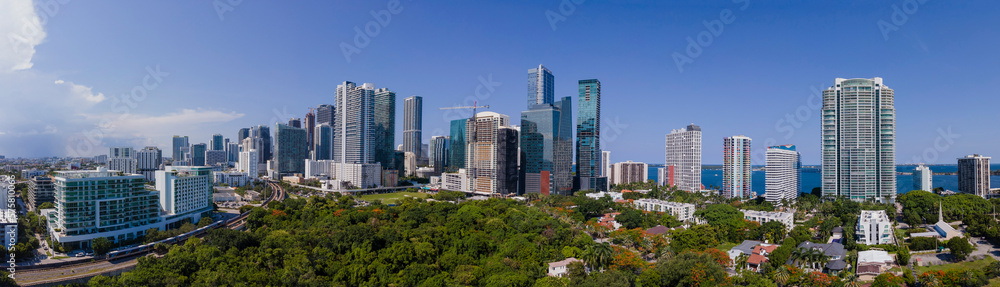 Beautiful Miami Florida skyline with lush green foliage against blue sky. Panorama of the city with skyscrapers, condominiums, apartments, and road. Beautiful Miami Florida skyline with lush green foliage against blue sky. Panorama of the city with skyscrapers, condominiums, apartments, and road.