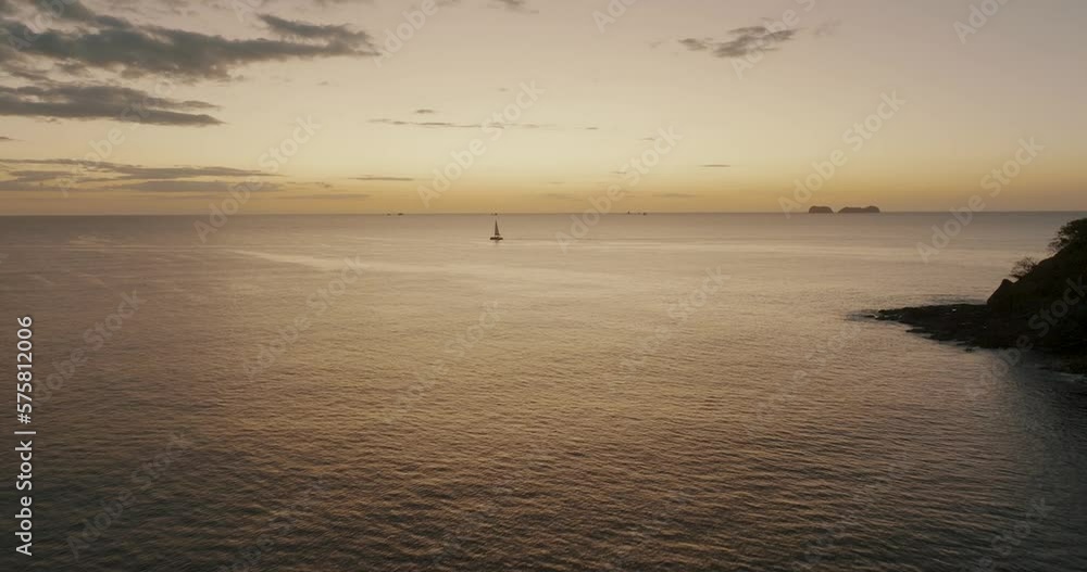 Isolated Sailboat Amidst Peaceful Ocean On Sunset In Guanacaste, Costa Rica. Aerial Drone Shot Isolated Sailboat Amidst Peaceful Ocean On Sunset In Guanacaste, Costa Rica. Aerial Drone Shot