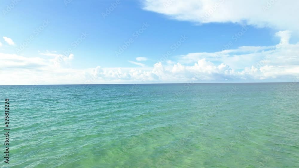 Drone flying low over white sand beach and clear emerald waters on a summer day with fluffy clouds in the sky on the Gulf of Mexico Pensacola Florida Drone flying low over white sand beach and clear emerald waters on a summer day with fluffy clouds in the sky on the Gulf of Mexico Pensacola Florida