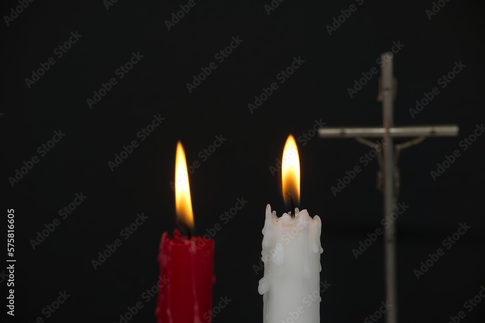 Two burning candles and Christian cross in the darkness Two burning candles and Christian cross in the darkness