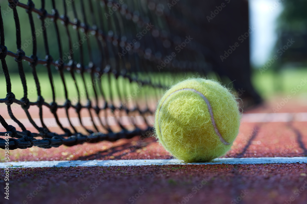 Tennis ball in the black net on hard tennis court surface