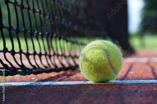 Tennis ball in the black net on hard tennis court surface © NetPix