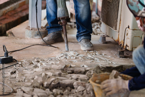 Foto labor using a jackhammer to break up concrete floor