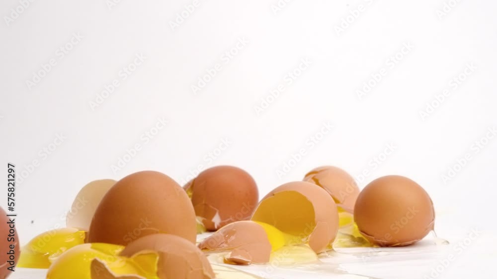 Brown eggs dropped and breaking in slow motion on white studio backdrop in 4k Brown eggs dropped and breaking in slow motion on white studio backdrop in 4k