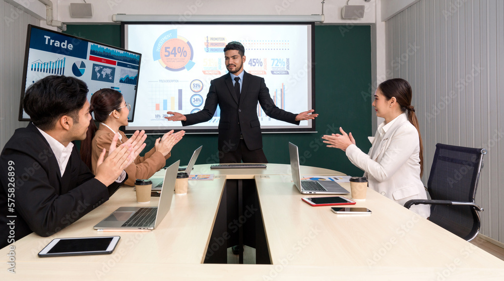 Businessman in black suit giving presentation with large digital monitor. Business executives team meeting in modern office with laptop computer, tablet, mobile phone and coffee on table. Businessman in black suit giving presentation with large digital monitor. Business executives team meeting in modern office with laptop computer, tablet, mobile phone and coffee on table.