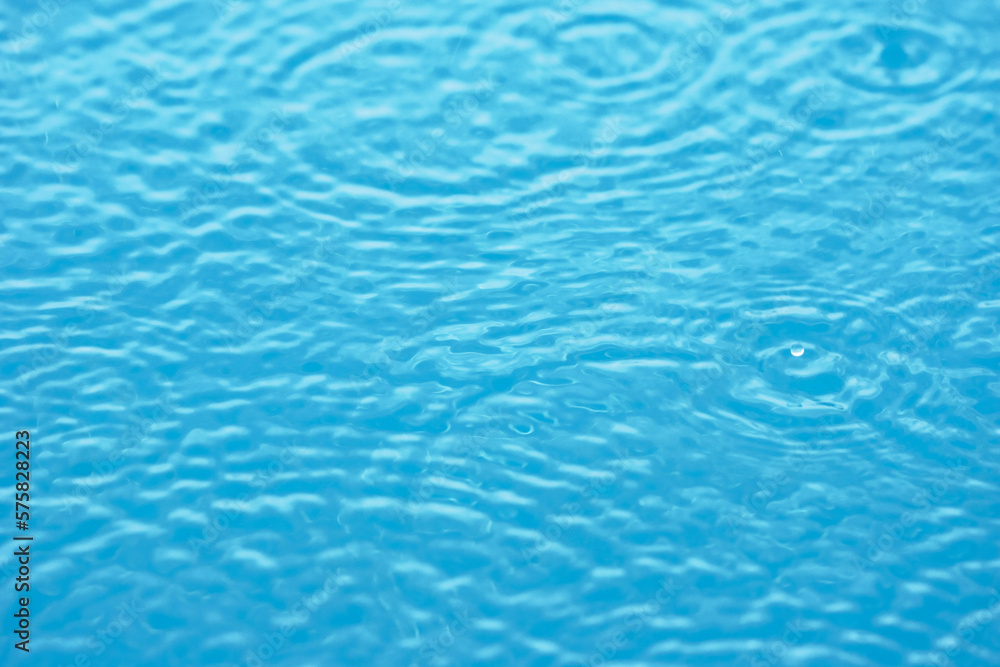 Defocused blurred transparent blue colored clear calm water surface texture.