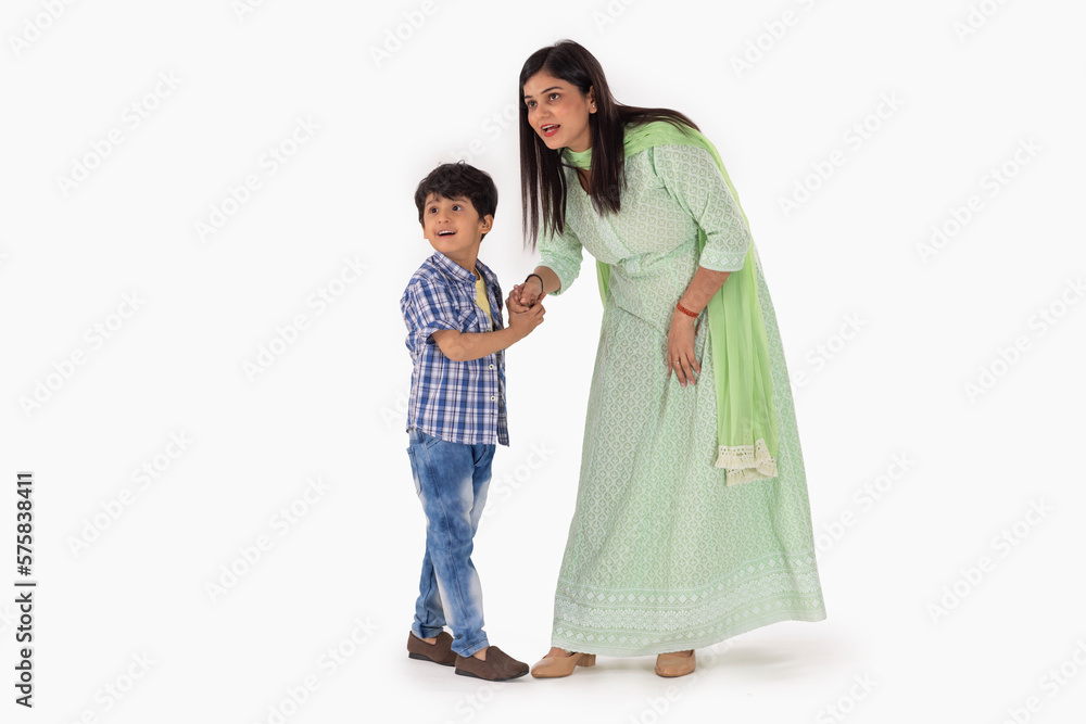 Portrait of cheerful mother and son looking away against white background