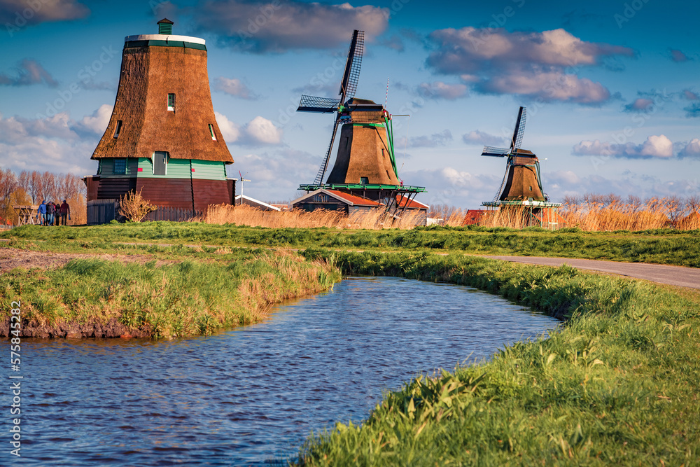 Authentic Zaandam lighthouse and windmills on the chore of famous channels in Zaanstad willage. Dramatic spring scene of Zaanse Schans, Netherlands, Europe. Traveling concept background. - obrazy, fototapety, plakaty 