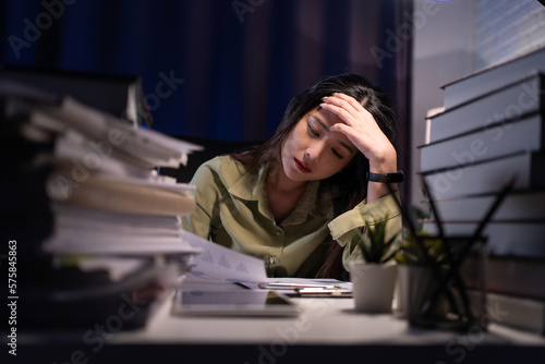 Woman working overtime on a desk at night photo