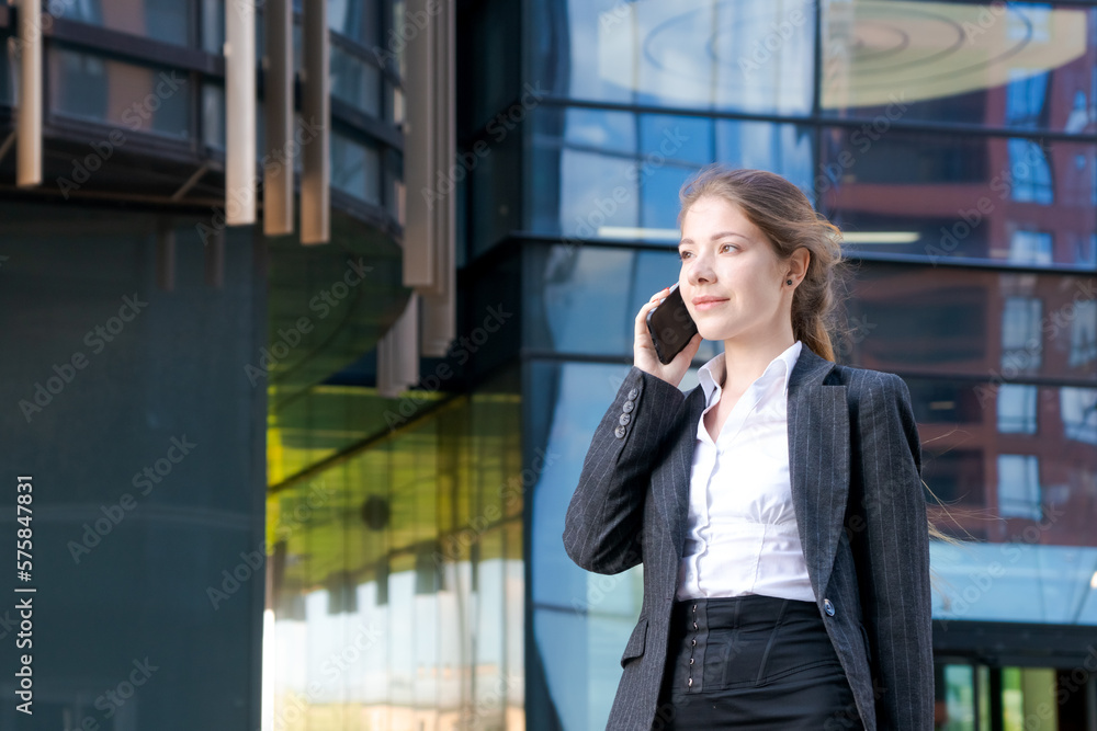 Business woman in suit uses smartphone. Big city with skyscrapers in background. Talking on the phone during the day Business woman in suit uses smartphone. Big city with skyscrapers in background. Talking on the phone during the day