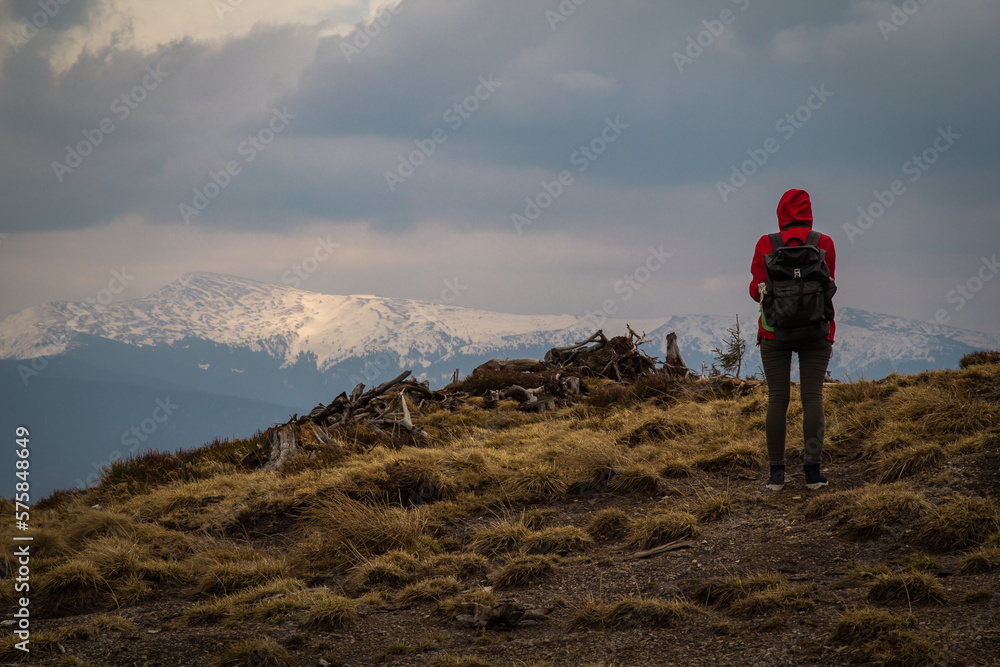 Female traveler looking at mountains scenic photography. Picture of hiker with cloudy background. High quality wallpaper. Natural light. Photo concept for ads, travel blog, magazine, article