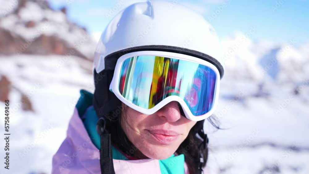Close-up ski helmet and ski glasses with reflection mountains in snow on face young woman. Girl wear sport clothing in winter resort. Portrait beautiful female. Enjoy healthy rest, active lifestyle. Close-up ski helmet and ski glasses with reflection mountains in snow on face young woman. Girl wear sport clothing in winter resort. Portrait beautiful female. Enjoy healthy rest, active lifestyle.