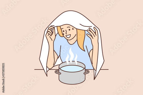 Woman sits over pot hot water covering head with towel to get rid cold or runny nose