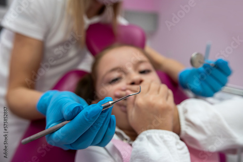 dentist is going to perform tooth filling procedure on a frightened child in  dental clinic.