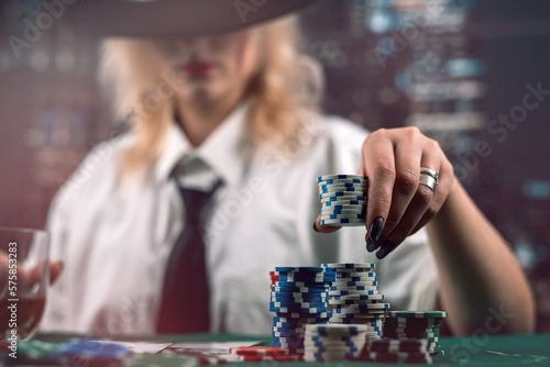 attractive girl holding cards and poker chips at casino table hiding her gaze photo