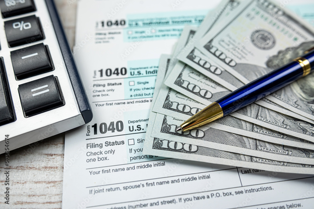 business accounting concept - 1040 tax form with pen calculator us dollar bills business accounting concept - 1040 tax form with pen calculator us dollar bills