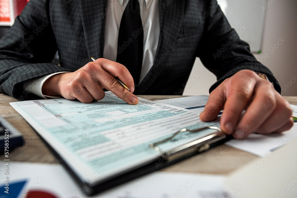 Man filling 1040 blank US tax form at the office Man filling 1040 blank US tax form at the office