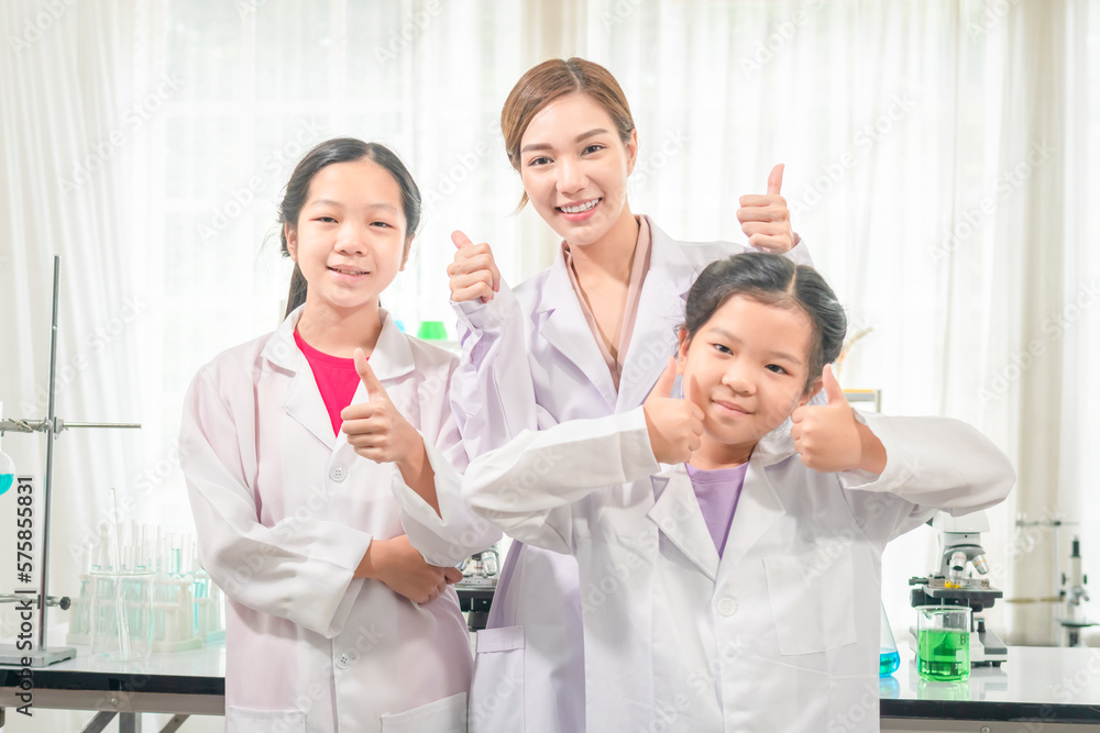 Elementary science class, Cheerful little kids with teacher scientist showing test bottle with chemistry liquid in school laboratory, Science laboratory Elementary science class, Cheerful little kids with teacher scientist showing test bottle with chemistry liquid in school laboratory, Science laboratory