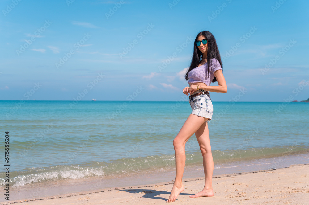 Summer lifestyle portrait of young girl enjoying on the tropical island. In the background the sea. Wearing Crop tops and shorts relaxed, Straight long hair.summer travel concept.