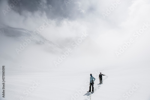 Two climbers on the Ruth Glacier navigating in low visibility conditions.