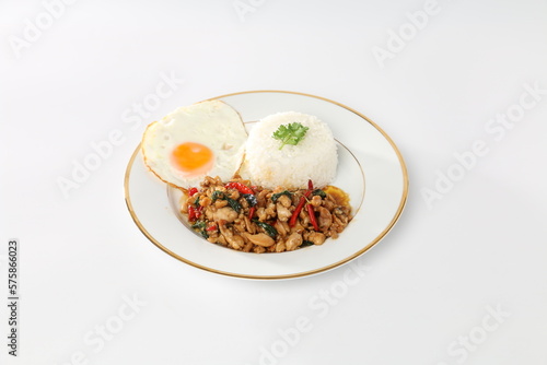 Rice topped with stir-fried chicken and holy basil, fried egg, and white plate.