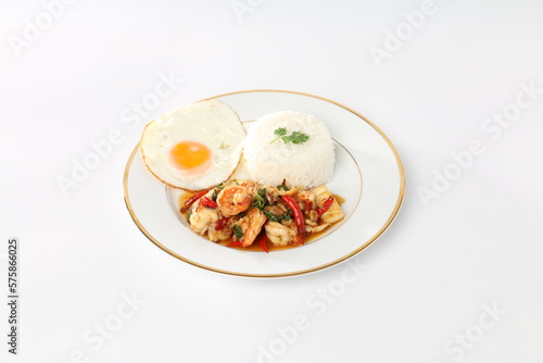 Rice topped with stir-fried seafood and holy basil, fried egg, white plate.