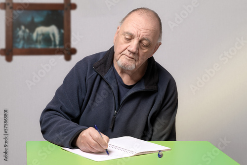 portrait homme âgé qui écrit à la main sur son bureau