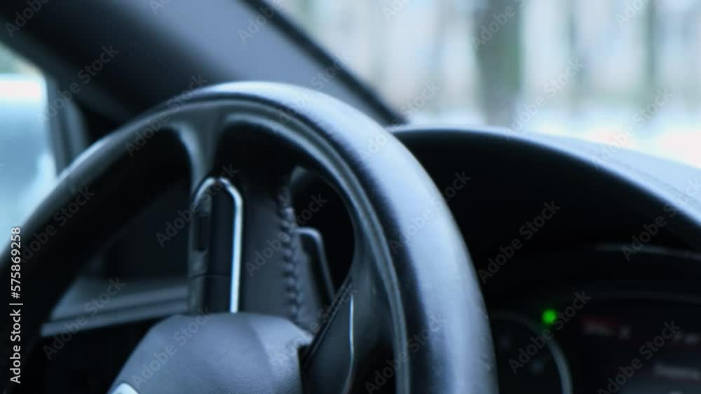 Selective focus man's hand on steering wheel, driving car in winter background. Black luxury modern car Interior. Steering wheel, shift lever and dashboard. Black leather Detail Automatic gear stick Selective focus man's hand on steering wheel, driving car in winter background. Black luxury modern car Interior. Steering wheel, shift lever and dashboard. Black leather Detail Automatic gear stick