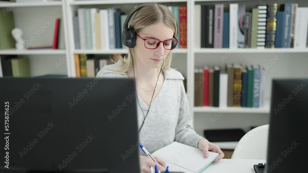Young blonde woman showing notebook on video call at library university Young blonde woman showing notebook on video call at library university