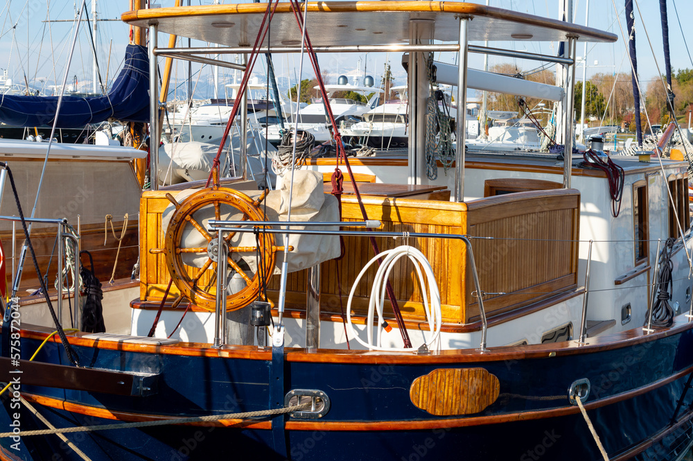 A very expensive wooden yacht in an Athens harbor. Wooden steering wheel.