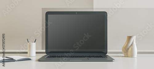Front view on blank black modern laptop monitor with place for web design, landing page or web site on white surface table among stand for pens and vase on light wall background. 3D rendering, mockup © Who is Danny