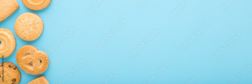 Different dry butter cookies on light blue table background. Pastel color. Closeup. Sweet snacks. Wide banner. Empty place for text. Top down view.