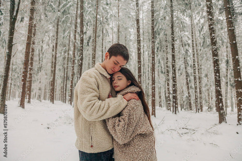 Teenage boyfriend hugging girlfriend in snowy forest Teenage boyfriend hugging girlfriend in snowy forest