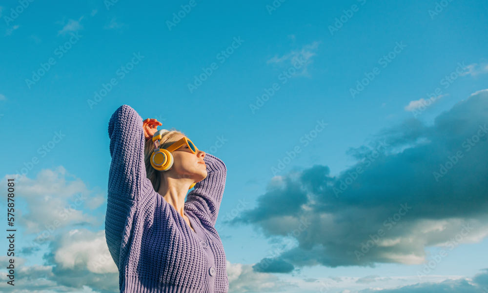 © Westend61 - Woman wearing wireless headphones listening to music on sunny day
